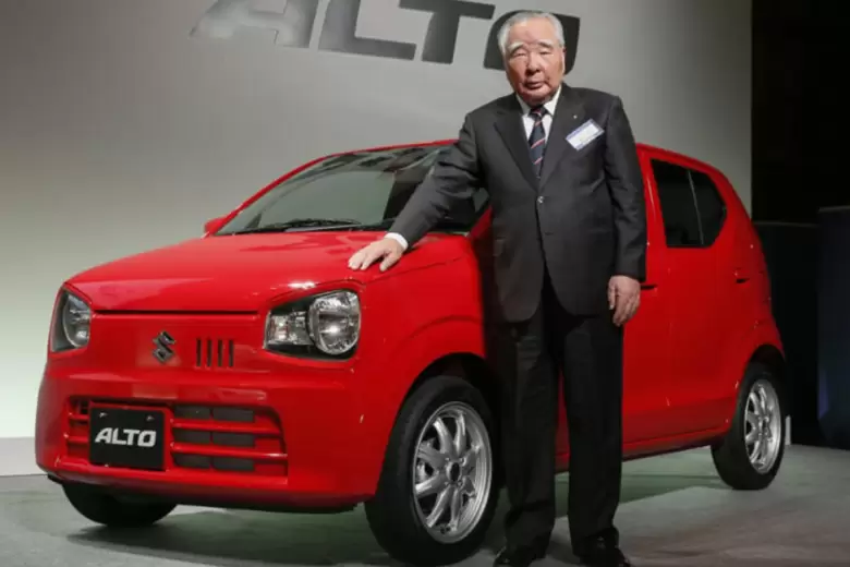 Osamu Suzuki junto al Alto, un city car que revolucionó la movilidad en países como India.