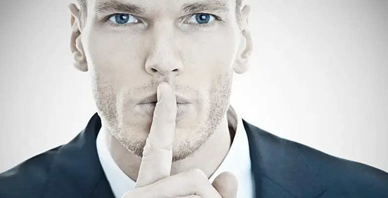 Un hombre haciendo un gesto de silencio poniendo su dedo índice sobre sus labios. Imagen de archivo.