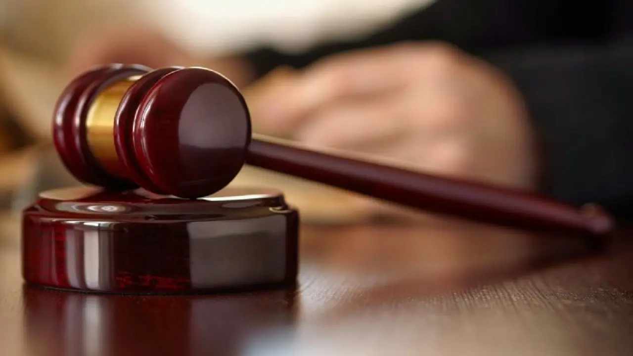 Martillo de la Justicia sobre una mesa y una mano borrosa por detrás 